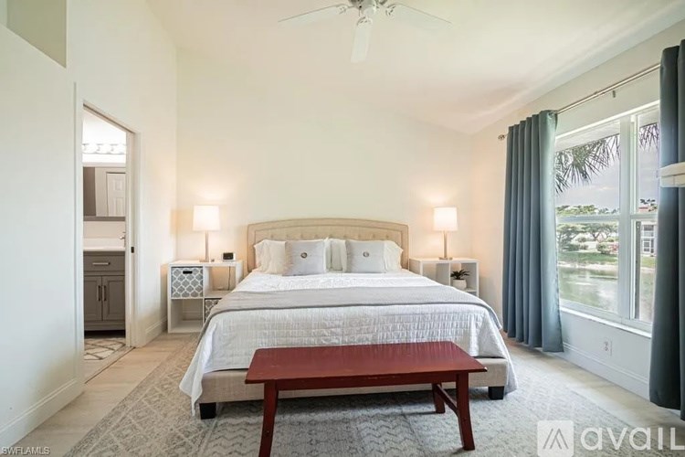 A bedroom with a large bed, a bench, and a ceiling fan.