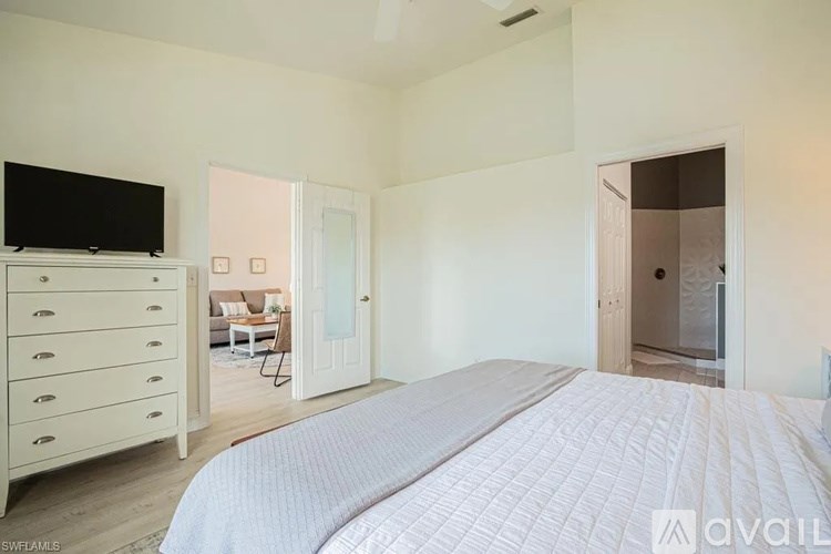 A bedroom with a large bed and a television on a dresser.
