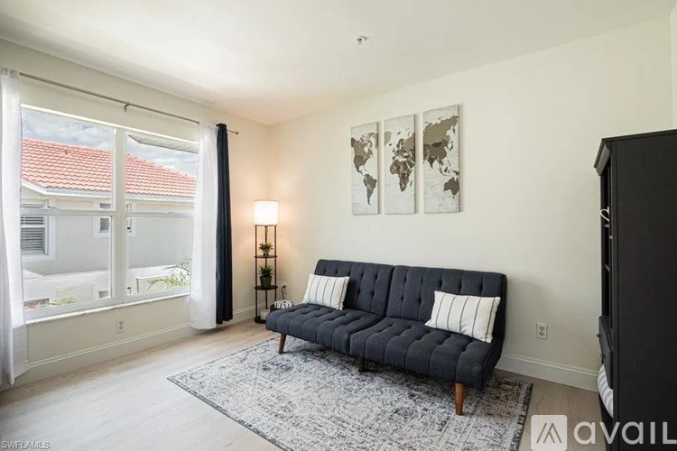 A living room with a black sofa and a world map on the wall.
