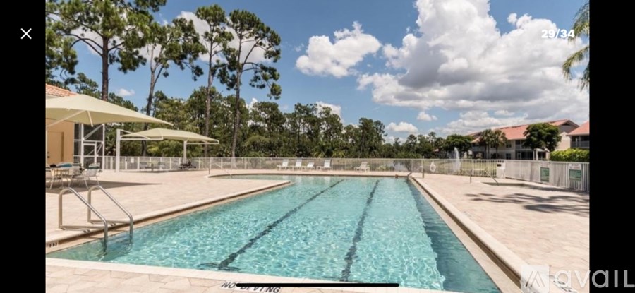 A large outdoor swimming pool surrounded by a fence and trees.