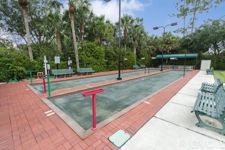 A tennis court with a red net and green benches.