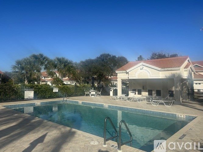 A pool with a metal ladder and a sign that says "available" in the foreground with a house and trees in the background.