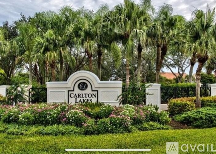 A sign that says Carlton Lakes in front of some trees.