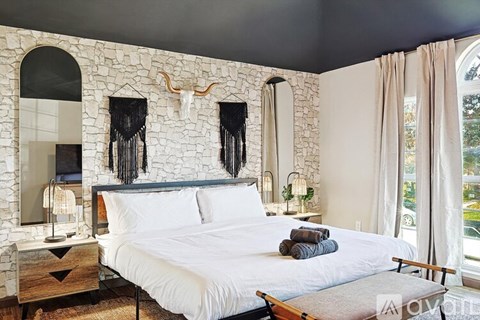 A bedroom with a stone wall and a bed with white bedding.