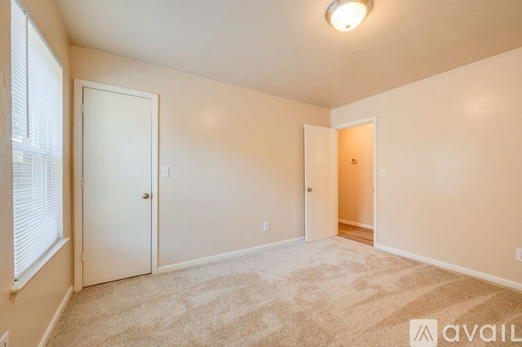 A room with a carpeted floor and two doors, one of which is open.