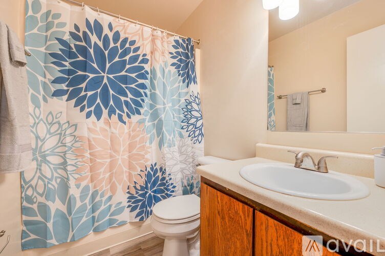 A bathroom with a white toilet, a sink, and a shower curtain with a floral pattern.