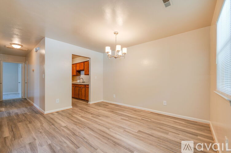 A spacious room with wooden flooring and a chandelier.