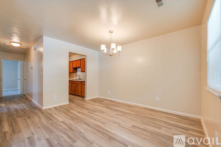 A spacious room with wooden flooring and a chandelier.