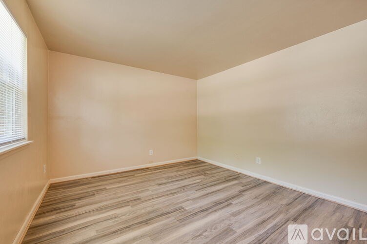 A room with wooden flooring and a window on the left side.