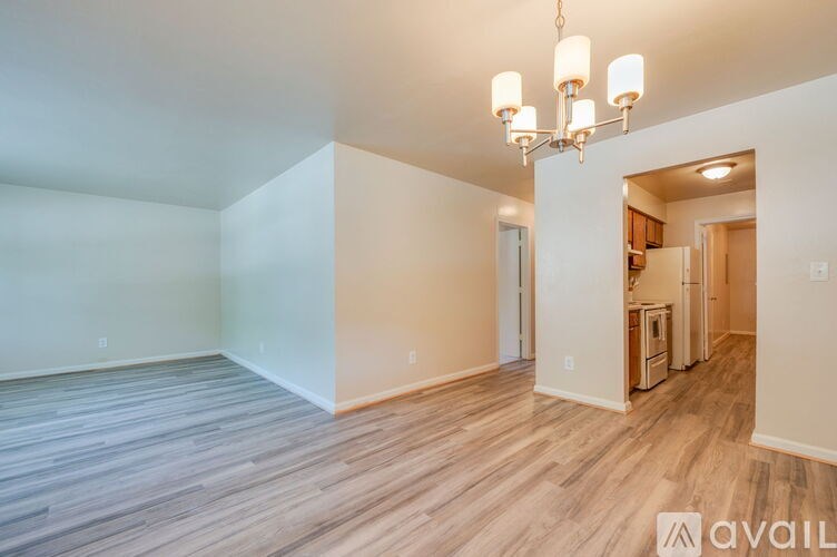 A spacious room with wooden flooring and a chandelier.