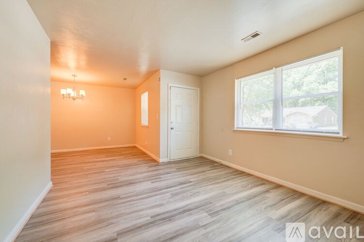 A room with wooden flooring and a window with a view of trees.