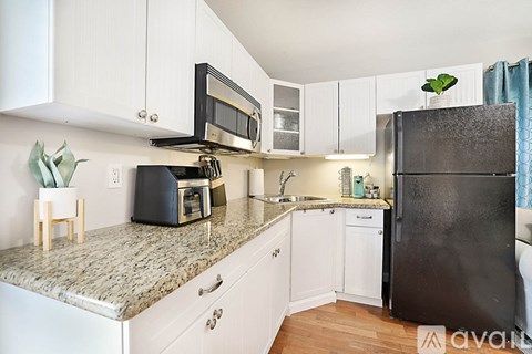 A kitchen with a black refrigerator and white cabinets.
