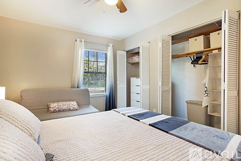 A bedroom with a large bed and a window with a view of trees.