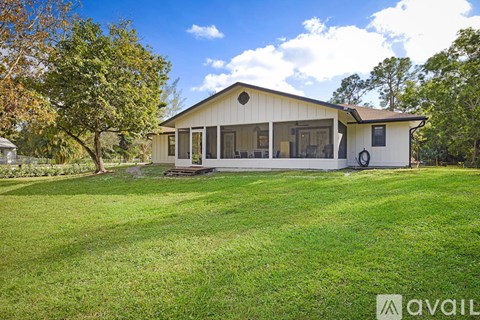 A house with a white exterior and a large lawn in front.