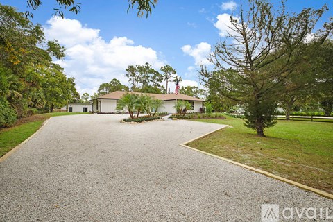 A house with a driveway and trees in front.