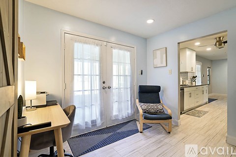 A well-lit room with a chair, desk, and a mirror.