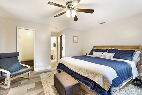A bedroom with a bed, chair, and ceiling fan.