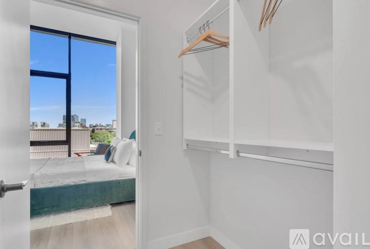 A bedroom with a bed, a window, and a closet with clothes hangers.