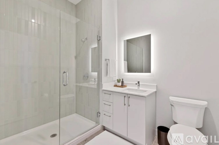 A white bathroom with a glass shower stall and a white toilet.