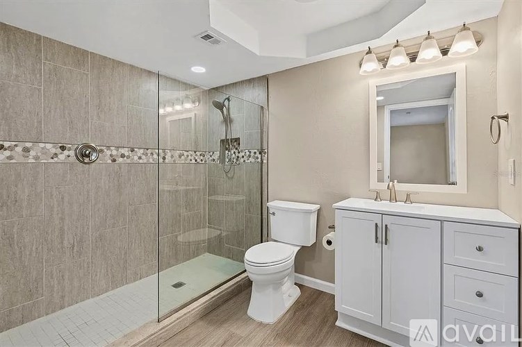 A bathroom with a walk-in shower, toilet, and sink.