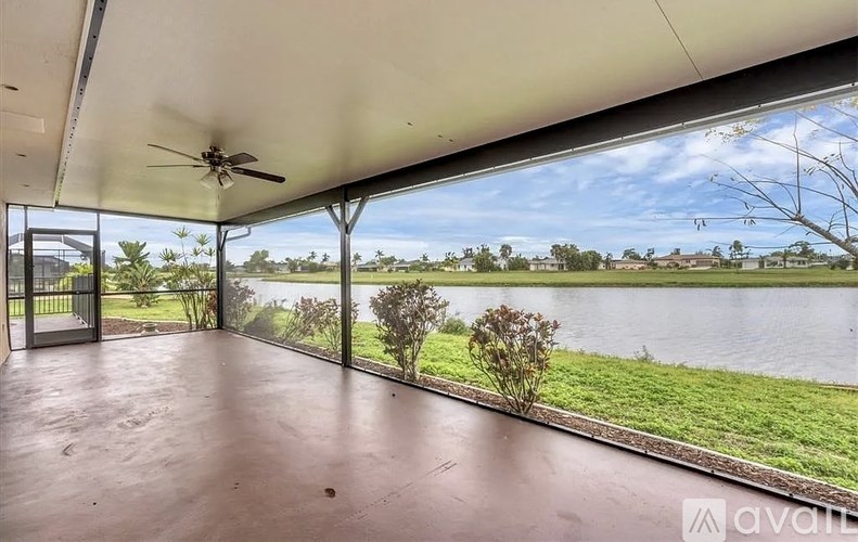 A room with a ceiling fan and sliding glass doors overlooking a body of water.