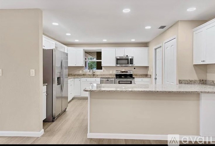 A kitchen with white cabinets and a granite countertop.