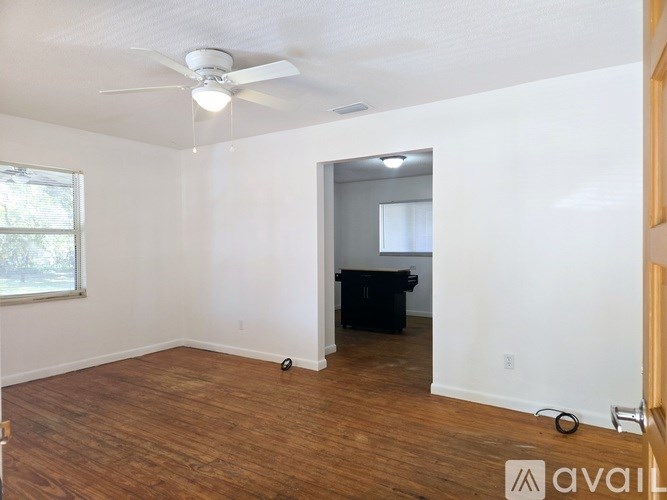 A room with a ceiling fan and a desk with a computer.