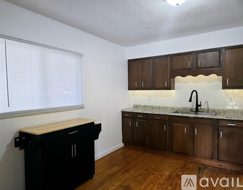 A kitchen with brown cabinets and a black island.