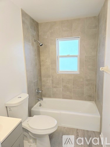 A bathroom with a toilet, a tub, and a window.
