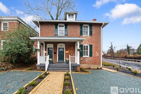 A red brick house with a green door and a porch.