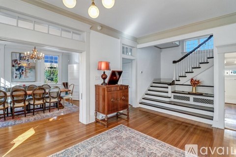 A spacious living room with a staircase and a dining table set up.