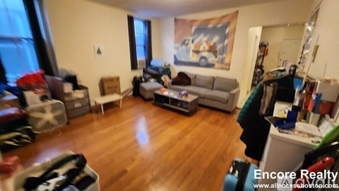 A living room with a grey couch and a painting on the wall.