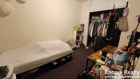 A bedroom with a bed, a table, and a closet.
