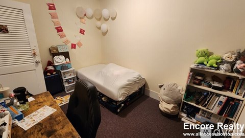 A room with a bed, a desk, and a bookshelf.