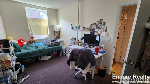A bedroom with a bed, desk, and chair.