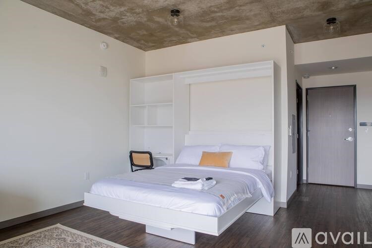 A bedroom with a white bed and a wooden floor.