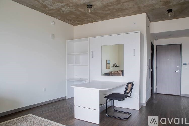 A room with a white desk and a black chair.