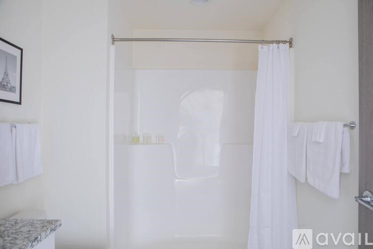 A white bathroom with a shower curtain and towels hanging on the wall.