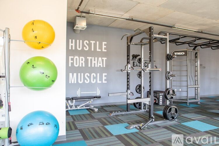 A gym with a sign that says "Hustle for that muscle" and exercise equipment.