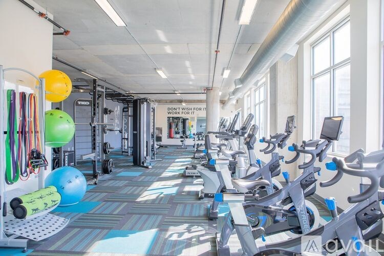 A gym with a variety of equipment and a sign that says "Don't wish for it, work for it."