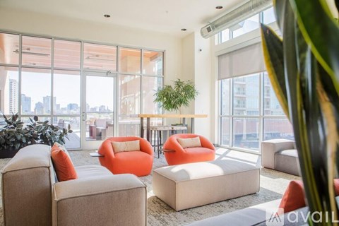 A living room with orange chairs and a large window overlooking a cityscape.