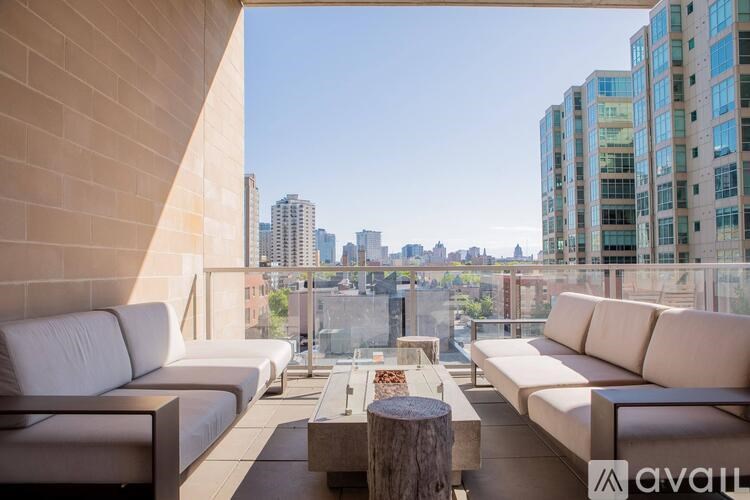A modern outdoor seating area with white couches and a wooden coffee table.