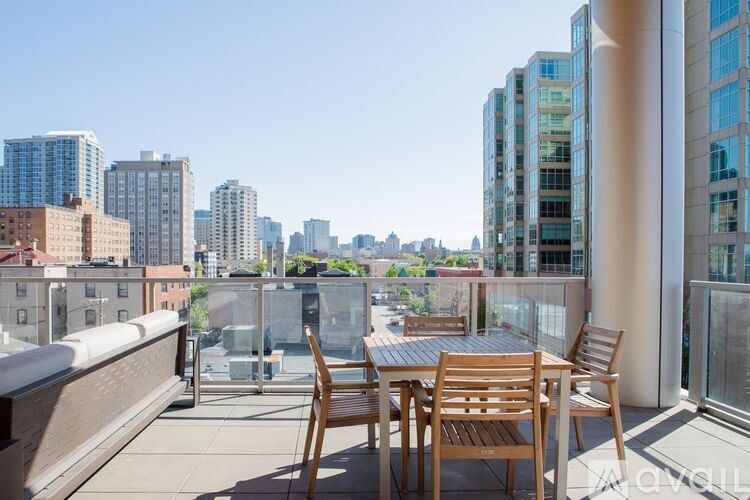 A balcony with a table and chairs overlooks a city skyline.