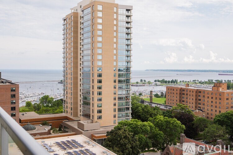 A tall building with many windows stands in front of a body of water.