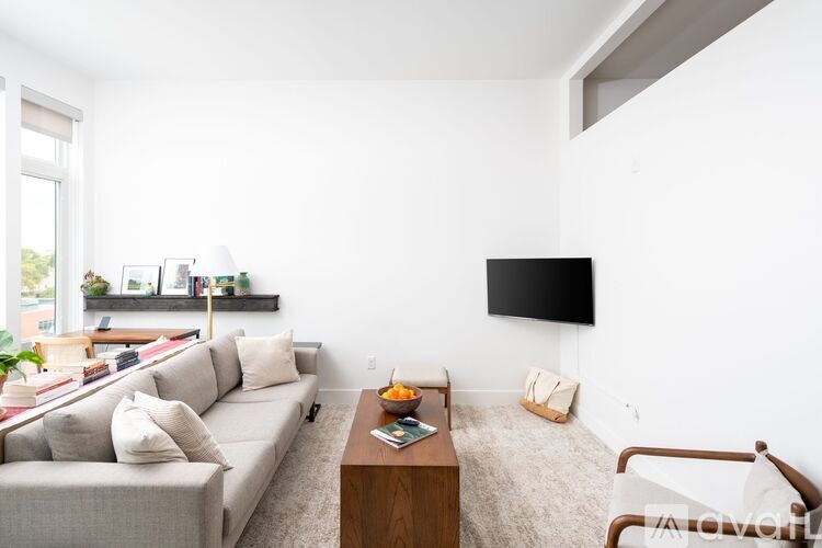 A living room with a grey couch, a wooden coffee table, and a flat screen TV mounted on the wall.
