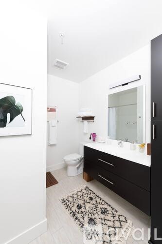 A bathroom with a toilet, sink, and a painting of a hat on the wall.