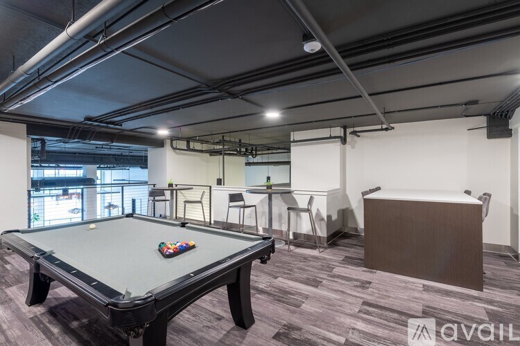 A pool table is in the middle of a room with a brown sofa.