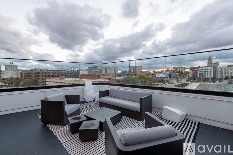 A modern outdoor seating area with black and white furniture overlooking a cityscape.