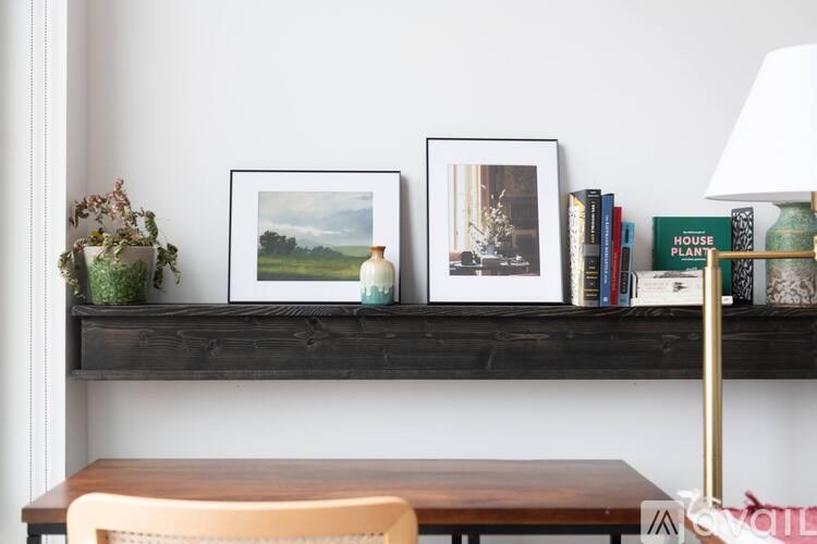 A shelf with a picture, books, and a lamp.