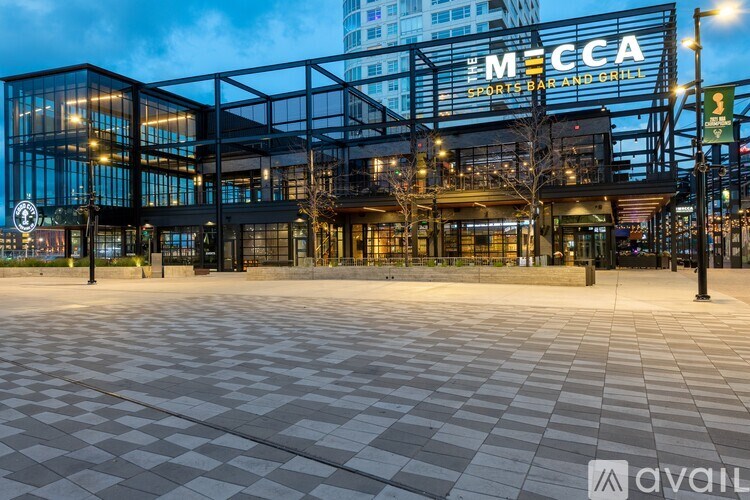 A large building with a glass facade and a sign that reads "MECCA SPORTS, PARK AND GRILL".